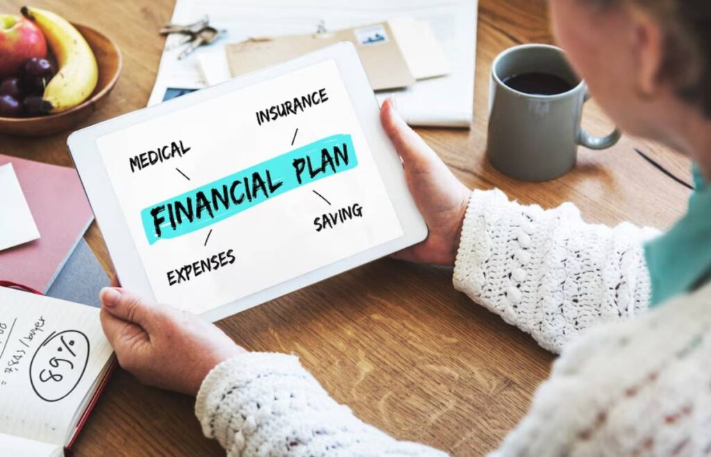 Older individual reviews a digital financial plan on a tablet, surrounded by notes and a cup of coffee.