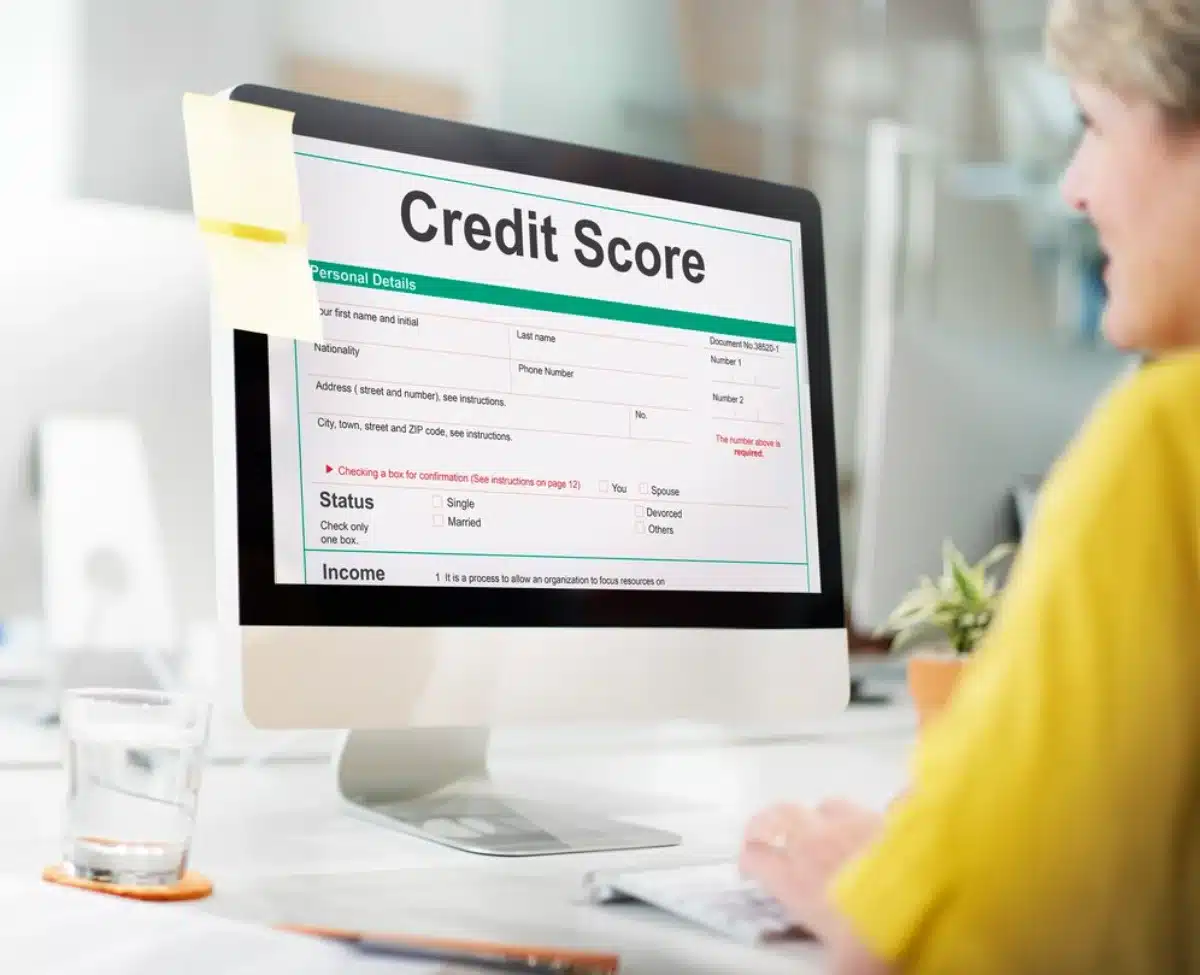 A person reviews their credit score details on a computer screen in a bright office setting.