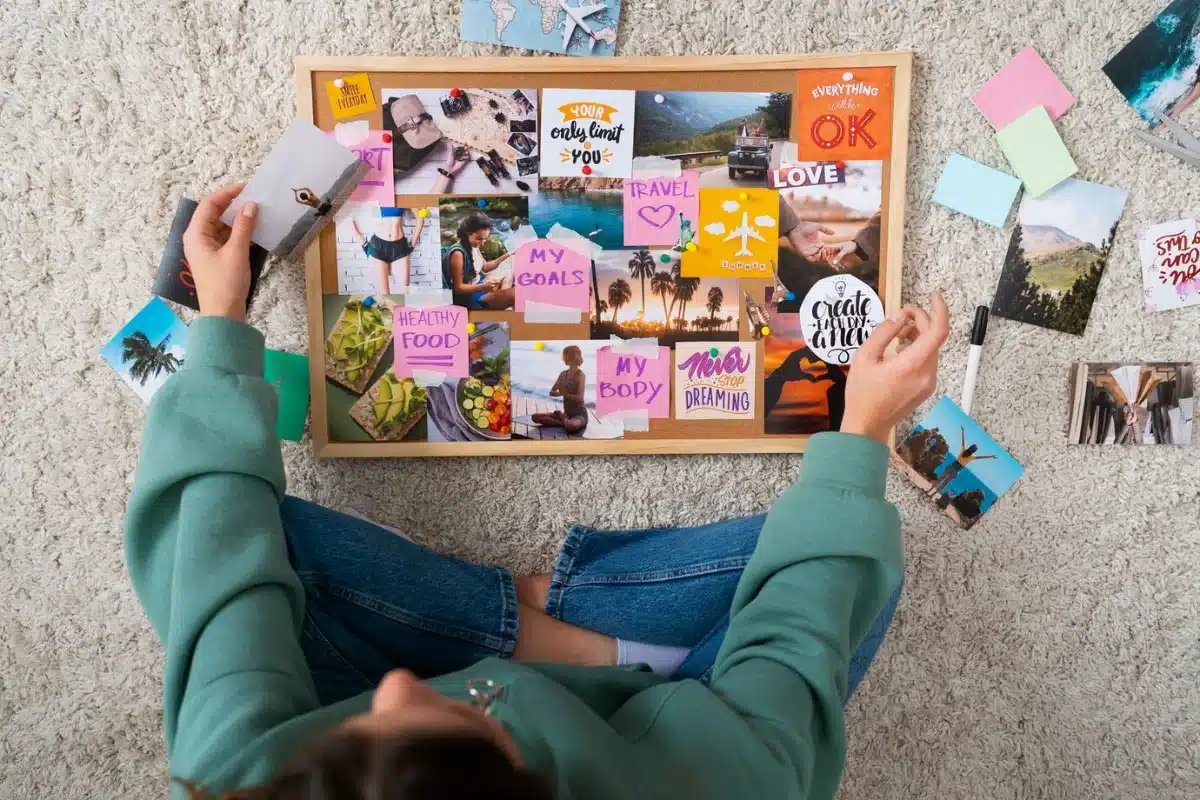 Person creating a vision board with various inspirational images and phrases laid out on the floor.